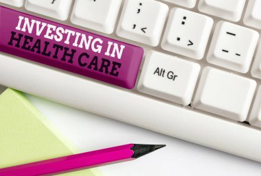 Sözcük yazma metni Yatırım Sağlık Hizmetleri. Sağlığın bakımı veya iyileştirilmesi üzerine para koymak için iş konsepti boş fotokopi alanına aksesuarlar yerleştirilmiş farklı renkli klavye anahtarı.
