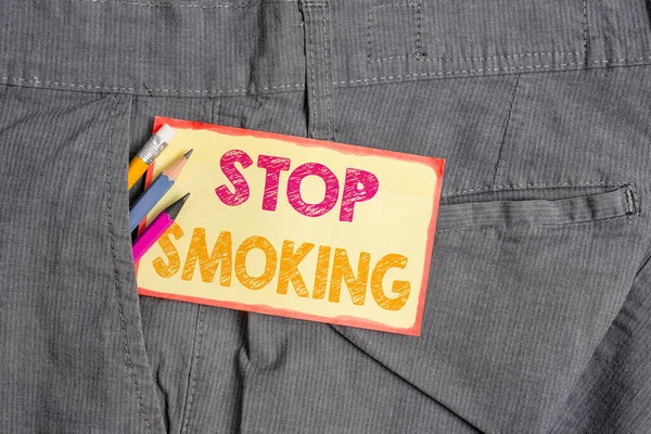 表示戒烟的概念手写。停止或停止使用吸烟成瘾书写设备和裤子口袋里的黄色便条. — 图库照片