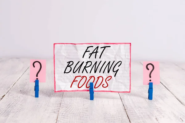 Handwriting text Fat Burning Foods. Concept meaning produce fat loss by stimulating metabolism to reduce appetite Scribbled and crumbling sheet with paper clips placed on the wooden table. — Stock Photo, Image