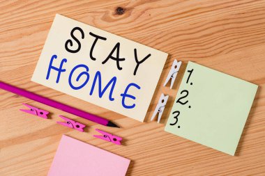 Stay Home Save Lives 'ı gösteren bir not yazıyorum. İş fotoğraflarının gösterilmesi, hastalıklı hastaların sayısını azaltmak için evi renkli çamaşır iğnesi kağıtları boş ahşap zemin zeminini hatırlatıyorlar.
