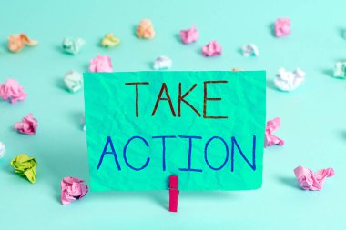 El yazısı Take Action. Kavram demek birine bir şey yapmasını ya da tepki vermesini tavsiye eder. Renkli buruşuk dikdörtgen şekilli hatırlatıcı kağıt açık mavi arkaplan.