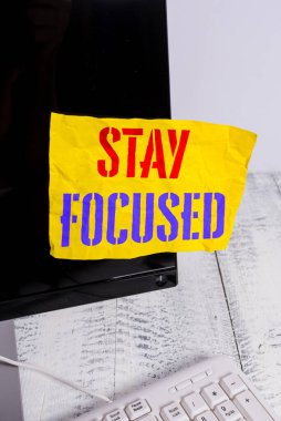 Odaklanmış Kalın 'ı gösteren not yazılıyor. İş fotoğrafı gösterimi Dikkatli ol Önceliği yoğunlaştır Görevden uzak dur Not kağıdı monitörü ekranı beyaz klavyenin yanında.