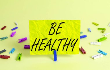 Sağlıklı Olun yazan bir mesaj. Kavramsal fotoğraf tam bir duygusal ve fiziksel refahı teşvik eder Renkli buruşuk dikdörtgen şekilli hatırlatıcı kağıt açık mavi arkaplan.