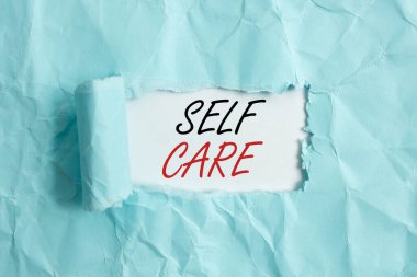 Kişisel Bakım 'ı gösteren bir mesaj. Kavramsal fotoğraf. Birisinin sağlığını korumak veya iyileştirmek için harekete geçme pratiği. Yırtılmış karton, ahşap klasik masa arkaplanının üzerine yerleştirilmiş..