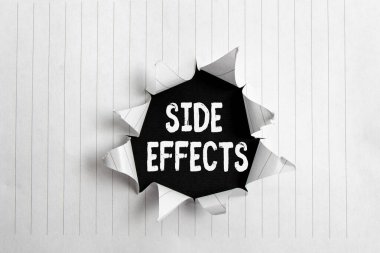 Yan etkilerini gösteren kavramsal el yazısı. Uyuşturucu ya da tıbbi tedavinin istenmeyen etkilerini gösteren bir iş fotoğrafı. Yırtılmış karton kaplama, ahşap klasik bir masanın üstünde..