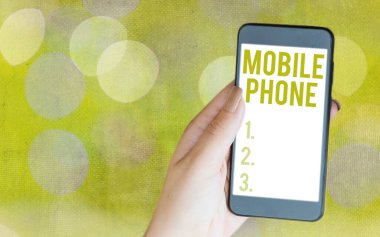 Cep telefonunu gösteren bir not yazıyorum. İş fotoğrafı görüntüleme Aramaları ve mesajları iletmek için kullanılan el bilgisayarı Renkli bokeh arkaplan altında modern aygıtlar beyaz ekran.