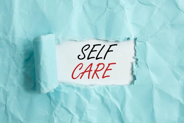 Text sign showing Self Care. Conceptual photo the practice of taking action to preserve or improve one s is health Rolled ripped torn cardboard placed above a wooden classic table backdrop. — Stock Photo, Image