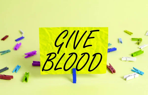 Textová značka "Give Blood". Konceptuální fotografie jednotlivce dobrovolně má odebranou krev a používá se pro transfuze Barevné zmačkané obdélníkový tvar upomínky papír světle modré pozadí. — Stock fotografie