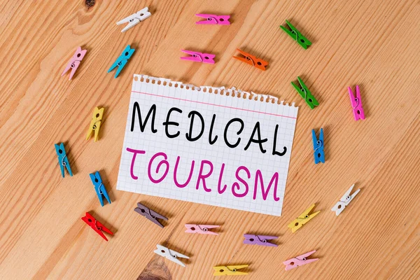 Conceptual hand writing showing Medical Tourism. Business photo showcasing traveling to another country seeking for medical care Colored crumpled papers wooden floor background clothespin.