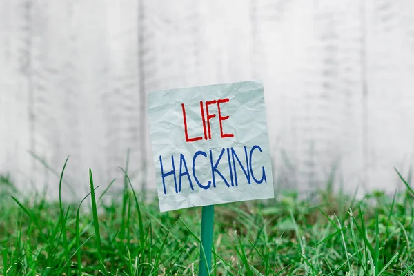 Handwriting text Life Hacking. Concept meaning Simple and clever techniques in accomplishing task easily Plain empty paper attached to a stick and placed in the green grassy land.