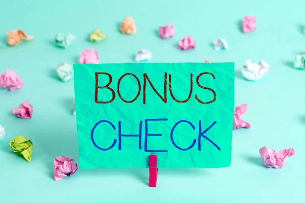 Handwriting text writing Bonus Check. Concept meaning something in addition to what is expected or strictly due Colored crumpled rectangle shaped reminder paper light blue background.