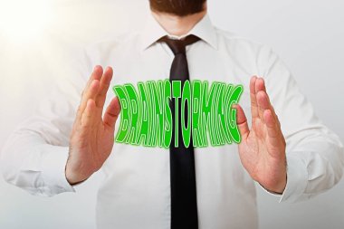 Beyin fırtınasını gösteren bir not yazıyorum. İş fotoğrafı gösterme çözme tekniği kendiliğinden katkı sağlama modelini içeriyor. El ile işaret ederek seyrüsefer ilerlemesini sembolize ediyor..