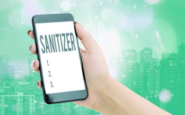 Dezenfektanı gösteren bir not yazıyorum. İş fotoğraflarının sergilendiği sıvı veya jel genellikle bulaşıcı ajanları azaltmak için kullanılır. Renkli bokeh arka plan altında modern cihazlar beyaz ekran.