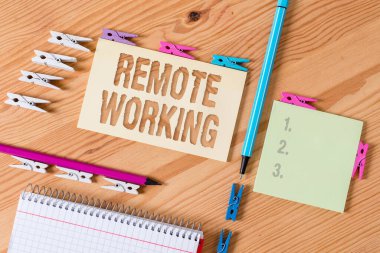 Uzaktan Çalışmayı gösteren not yazılıyor. İş fotoğraflama tarzı profesyonellerin ofis dışında çalışmasını sağlıyor. Renkli çamaşır iğnesi kağıtları boş ahşap zemin ofisini hatırlatıyor..