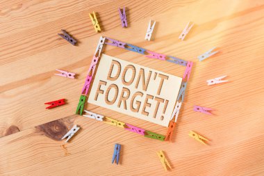 Kelime yazma metni unutma. Birine önemli bir gerçeği veya detayı hatırlatmak için iş konsepti. Renkli çamaşır iğnesi kağıtları boş hatırlatıcı ahşap zemin ofis.