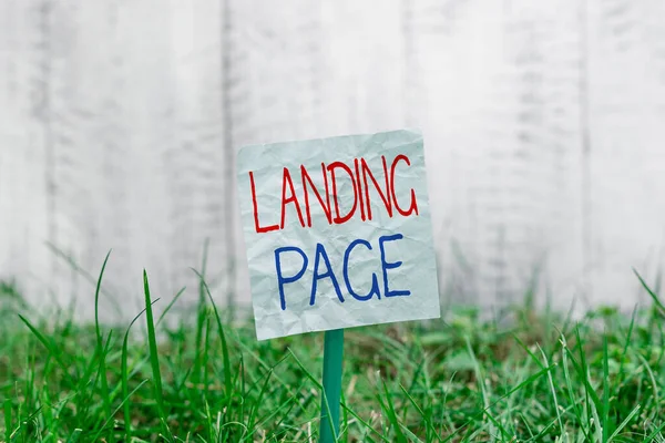 Handwriting text Landing Page. Concept meaning Website accessed by clicking a link on another web page Plain empty paper attached to a stick and placed in the green grassy land. — Stock Photo, Image