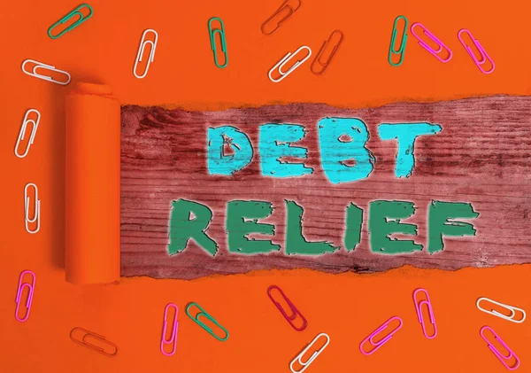 Writing note showing Debt Relief. Business photo showcasing partial or total remission of it especially those by countries Rolled ripped torn cardboard above a wooden classic table.