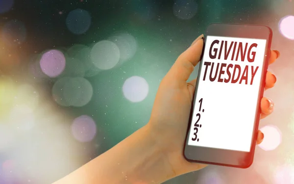 Conceptual hand writing showing Giving Tuesday. Business photo showcasing international day of charitable giving Hashtag activism Modern gadgets white screen under colorful bokeh background.