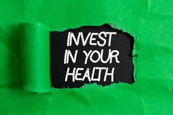 あなたの健康への投資を書く手書きテキスト。概念的な意味あなたの健康の維持か改善にお金を置く木製の古典的なテーブルの背景の上に置かれた引き裂けた段ボールを転がし. — ストック写真
