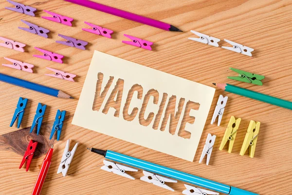 Skrivtext Vaccin. Begreppet innebär beredning av dödade mikroorganismer eller levande försvagade organismer Färgade klädnypor papper tom påminnelse trägolv bakgrund kontor. — Stockfoto