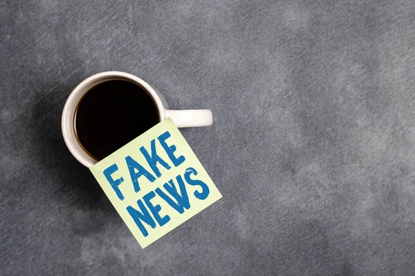 Woord dat tekst schrijft Fake News. Bedrijfsconcept voor valse informatie publiceren onder het mom van authentiek nieuws Papier accessoires met digitale smartphone op verschillende achtergrond. — Stockfoto