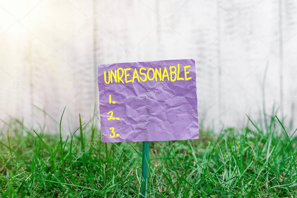 Conceptual hand writing showing Unreasonable. Business photo text not conformable to reason or exceeding the bounds of reason Plain paper attached to stick and placed in the grassy land.