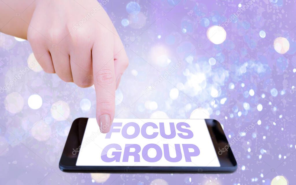 Text sign showing Focus Group. Conceptual photo showing assembled to participate in discussion about something Modern gadgets with white display screen under colorful bokeh background.