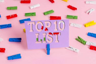 İlk 10 Listesi 'ni yazan el yazısı metni. Kavram derken, belirli bir listedeki en önemli ya da en başarılı on öğeyi kastediyorum. Renkli çamaşır iğnesi kağıtları boş hatırlatıcı, pembe zemin ofis pimi..