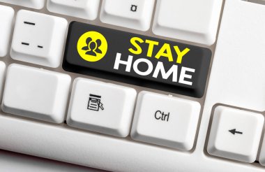 Stay Home 'u gösteren bir not yazıyorum. İş fotoğrafı gösterimi bir etkinlik için dışarı çıkmayın ve evde ya da evde kalın. Boş kopya alanına aksesuarlar yerleştirilmiş renkli klavye anahtarı.