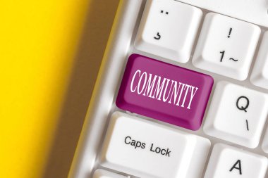 Conceptual hand writing showing Community. Business photo showcasing group of showing with a common characteristics living together Colored keyboard key with accessories arranged on copy space. clipart