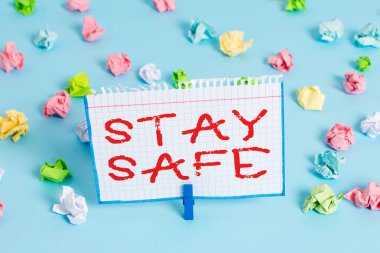 El yazısı. Güvenli Kal. Tehlike, zarar ya da makaleleri saklama tehdidinden korunmak anlamına gelen kavram. Renkli buruşmuş kağıtlar boş hatırlatıcı mavi zemin çamaşır mandalı.