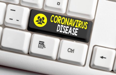 Coronavirus Hastalığı 'nı gösteren bir not yazıyorum. İş fotoğrafı gösterimi, yeni bir virüs olan SARSCoV2 'nin neden olduğu hastalık olarak tanımlanır. Boş kopya alanındaki aksesuarlarla donatılmış klavye anahtarı.