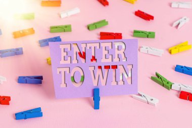 El yazısı metni yazan Enter To Win. Renkli mandal kağıtları boş hatırlatıcı, pembe zemin ofis broşu için değer değişimi veya kazanma şansı kavramı.