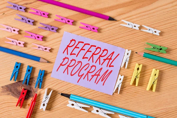 Text sign showing Referral Program. Conceptual photo employees are rewarded for introducing suitable recruits Colored clothespin papers empty reminder wooden floor background office.