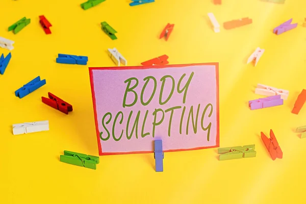 Writing note showing Body Sculpting. Business photo showcasing activity of increasing the body s is visible muscle tone Colored clothespin papers empty reminder yellow floor background office.