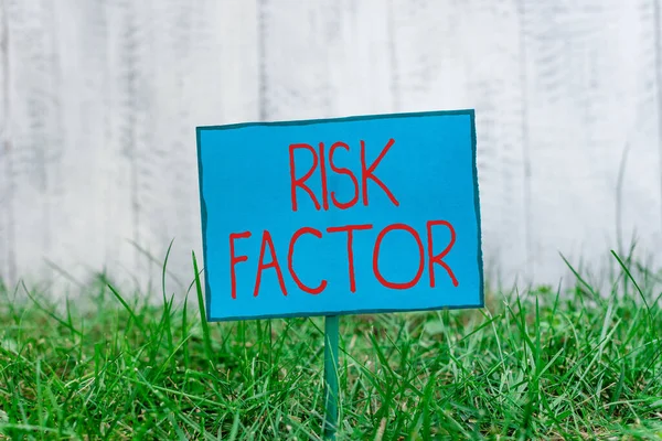 Conceptual hand writing showing Risk Factor. Business photo showcasing Characteristic that may increase the percentage of acquiring a disease Plain paper attached to stick and placed in the grassy — Stock Photo, Image