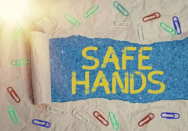 Writing note showing Safe Hands. Business photo showcasing Ensuring the sterility and cleanliness of the hands for decontamination Rolled ripped torn cardboard above a wooden classic table.