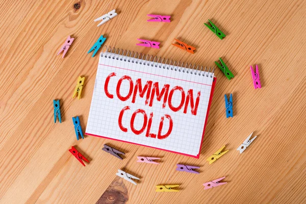 Tekst pisma Common Cold. Koncepcja oznaczająca zakażenie wirusowe górnych dróg oddechowych dotykające głównie nosa Kolorowe szpilki do ubrań puste przypomnienie drewniane podłogi biuro tła. — Zdjęcie stockowe