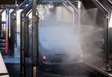 Otomatik bir oto yıkamada sprey le yıkanan araba, parlak mor, kırmızı ve sarı gösterge ışıkları açık