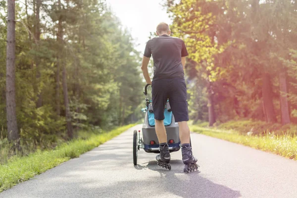 Joven en línea patinaje al aire libre con cochecito de bebé —  Fotos de Stock