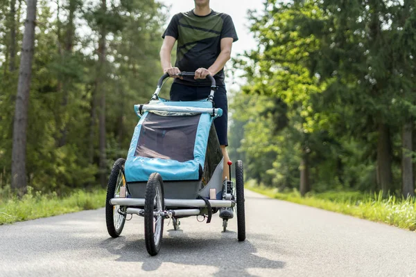 Ung man i linje skridskoåkning utomhus med barnvagn — Stockfoto