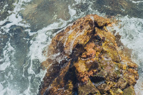 Foto de hermosa superficie de agua de mar turquesa transparente con ondulaciones y salpicaduras brillantes en el fondo del paisaje marino de piedra, imagen horizontal —  Fotos de Stock