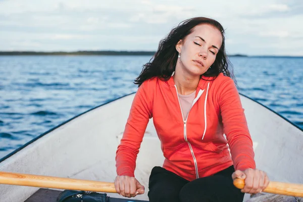 Удивительно красивая волосатая девушка плавает на деревянной лодке и греется веслами в великолепном весеннем озере. Стиль жизни без косметики — стоковое фото