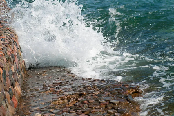 石の風景の背景に波紋と明るいスプラッシュと美しいクリアターコイズブルーの海の水の表面の写真、水平方向の画像 — ストック写真