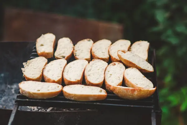Много ломтиков жареного багетного хлеба на гриле над огнем на свежем воздухе — стоковое фото