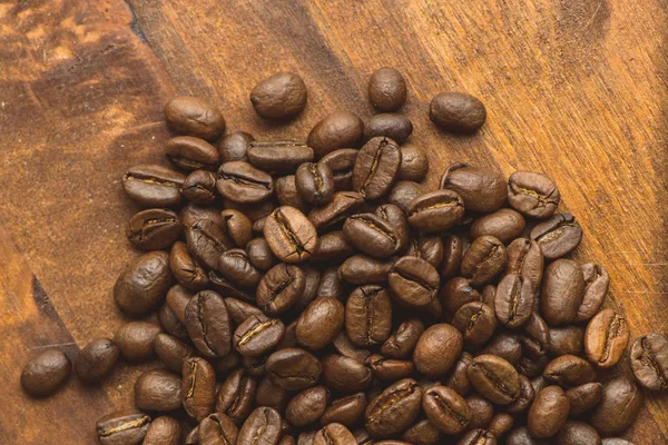 Brown coffee beans in circle shape, closeup of macro coffee beans for background and texture. On brown wooden board.