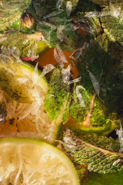 Carbonated soda water or juice with lime and mint in a glass jug. Macro closeup