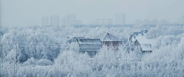 Gyönyörű fagyos behavazott, Oroszország. A csoport lakossági Tájházak, a közepén a kép és a városi sokemeletes épületek a háttérben — Stock Fotó