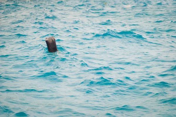 Une cartouche en plastique noir flotte dans la mer. Déchets ménagers, notion de manque de respect de l'environnement — Photo