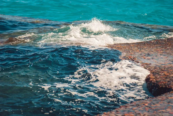 美丽清澈的碧绿海水表面与波纹和明亮的飞溅在石头海景背景，水平图片 — 图库照片